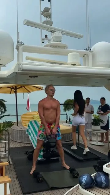 Alec Monopoly exercising with weights on the yacht's deck