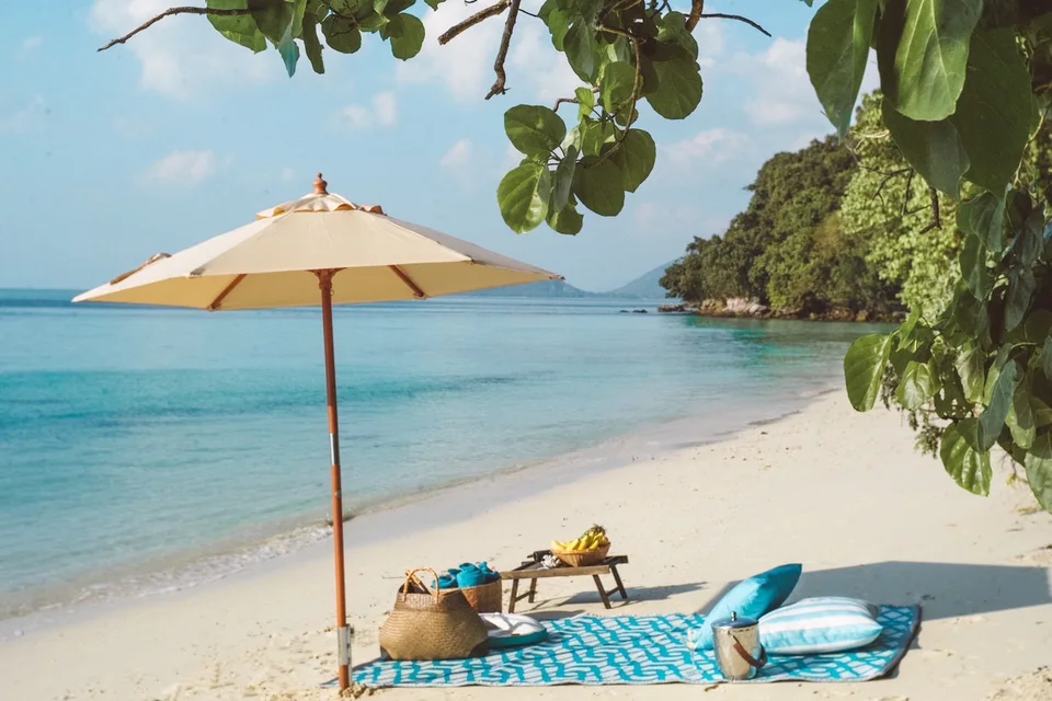 Picnic cushions and a low table set on the sand beside the sea
